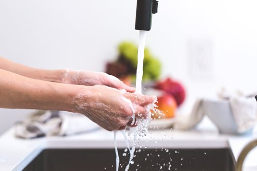 senior lady washing her hands at the kitchen sink