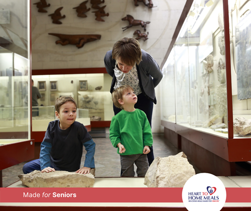 two young boys at the museum with their grandmother playing with rocks