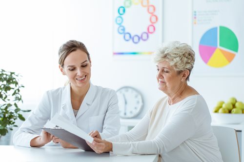 senior women sitting at table talking with a female doctor looking at paper