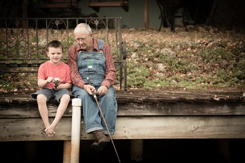 grandfather sitting on a dock with grandson fishing