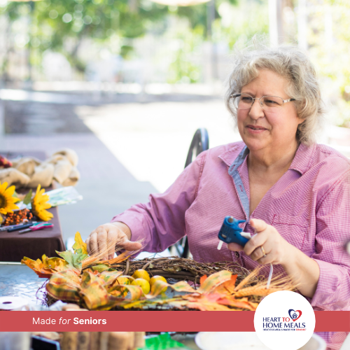 Senior women sitting outside making a craft wreath with a glue gun