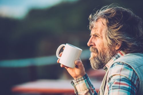 elder gentleman drinking coffee outside with the wind blowing his hair