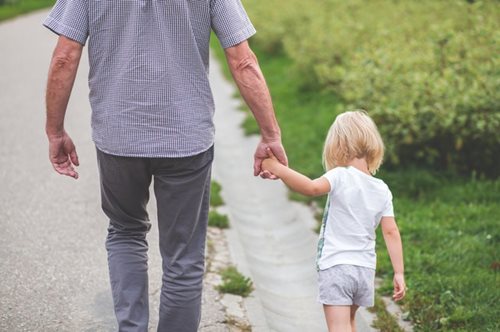 grand father walking holding grand daughters hand