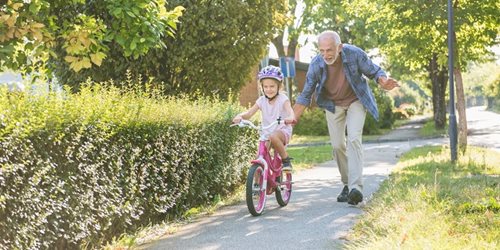 grand father teaching grand daughter to ride a bike