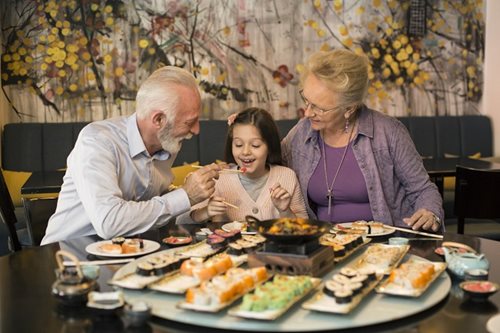 grandparents eating a sushi dinner with grand daughter